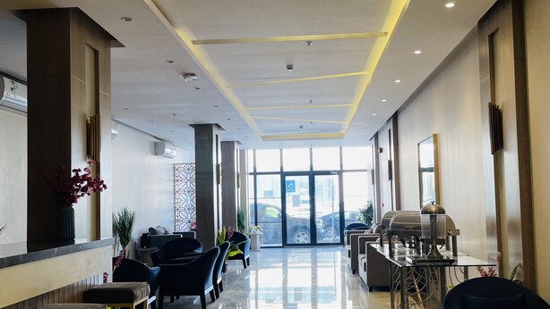 Eine Hotellobby mit einer langen Rezeption, einer Sitzecke und Blick ins Freie.