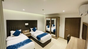 Ein Hotelzimmer mit zwei Betten, einem Kleiderschrank, einem Schreibtisch und einem Spiegel.