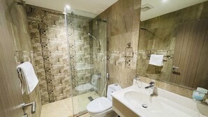Ein modernes Badezimmer mit einer Duschkabine, einer weißen Toilette und einem großzügigen Waschbecken mit Spiegel.