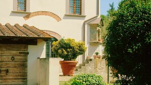A building with a tiled roof, a wooden door, and a large potted plant in the foreground. - Limoni Appartment (firenze)
