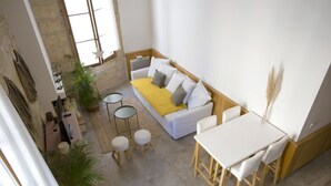 A modern living room with a white sofa, yellow throw, and a dining area with a white table and chairs. - L'Esprit Montpel "Face à l'Eglise St Roch" (Montpellier Spirit) (Montpellier)
