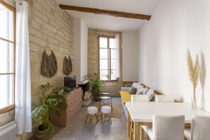A cozy living room with a stone wall, a fireplace, a sofa, a dining table, and various plants. - L'Esprit Montpel "Face à l'Eglise St Roch" (Montpellier Spirit) (Montpellier)