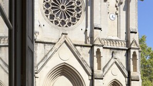 A cathedral with a large rose window, two green doors, and a staircase leading to the entrance. - L'Esprit Montpel "Face à l'Eglise St Roch" (Montpellier Spirit) (Montpellier)