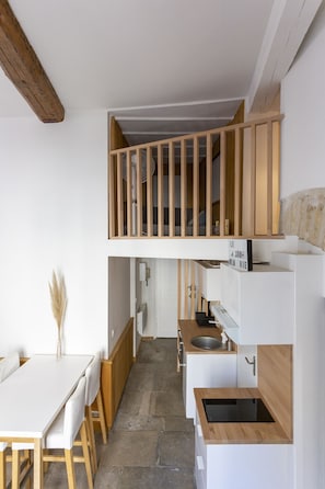 A compact kitchen with a wooden dining table, a built-in bench, and a small island with a sink. - L'Esprit Montpel "Face à l'Eglise St Roch" (Montpellier Spirit) (Montpellier)