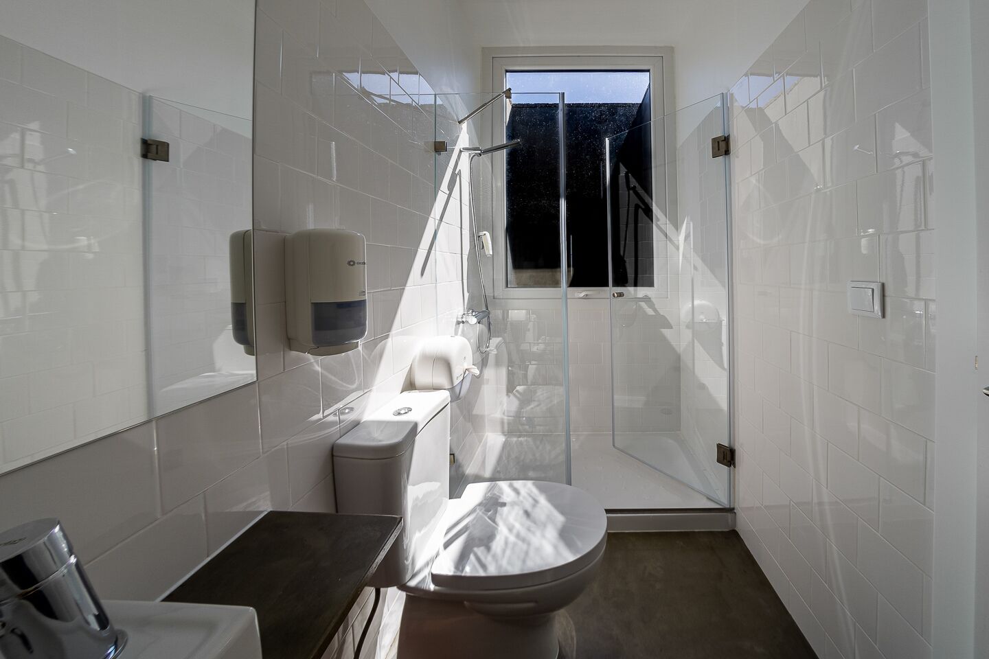 Un baño moderno con inodoro, lavabo y zona de ducha.