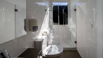 Un baño moderno con inodoro, lavabo y zona de ducha.