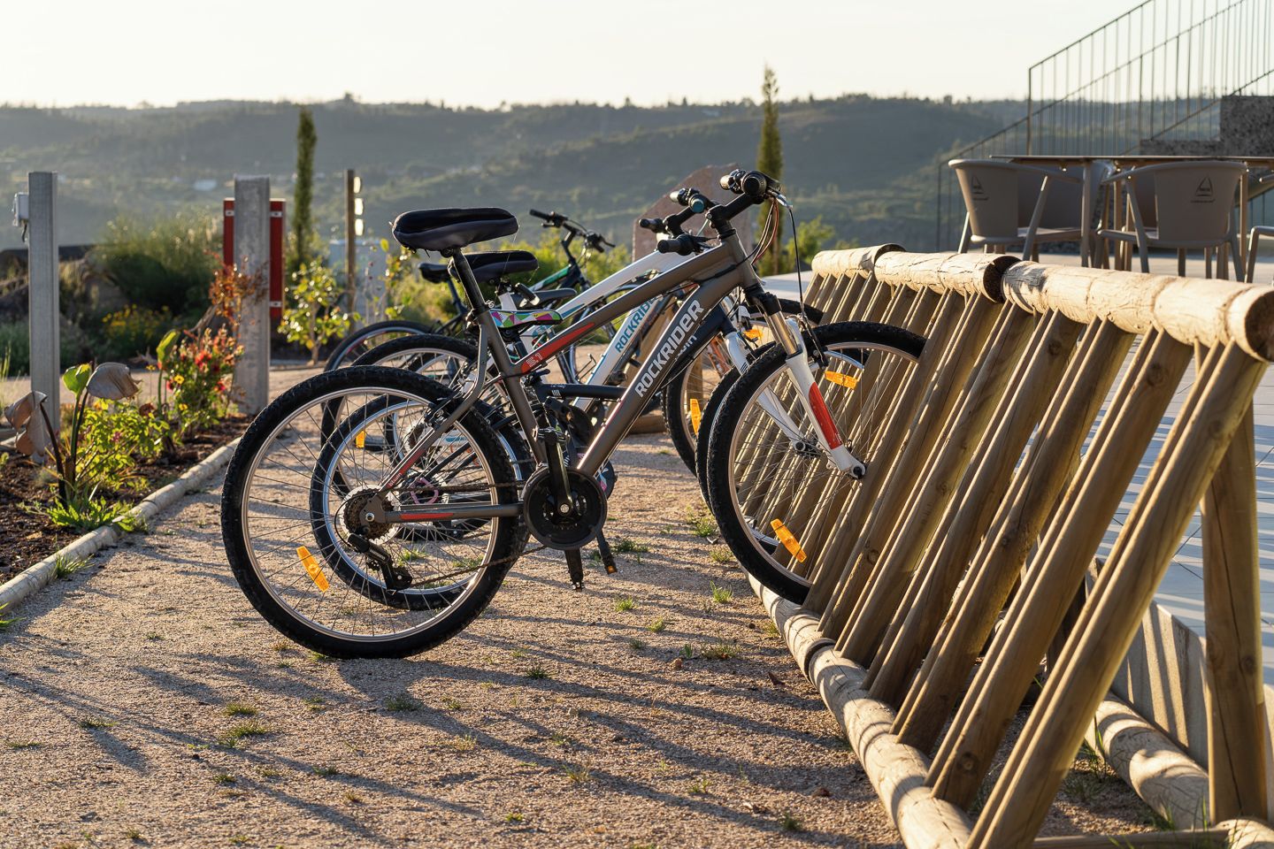 A bicycle parked next to a wooden fence with a gravel path and a scenic view in the background.