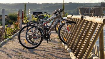 A bicycle parked next to a wooden fence with a gravel path and a scenic view in the background.
