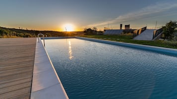 Una piscina al aire libre, sombrillas, sillones reclinables de piscina