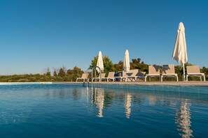 Una piscina al aire libre, sombrillas, tumbonas
