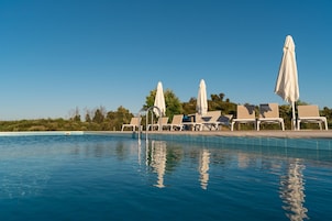 Una piscina al aire libre, sombrillas, tumbonas
