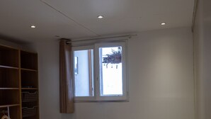 A bedroom with a single bed, a wooden wardrobe, and a window with curtains.
