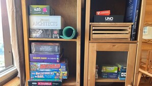 A wooden bookshelf with various board games, including 'Monopoly' and 'UNO'.