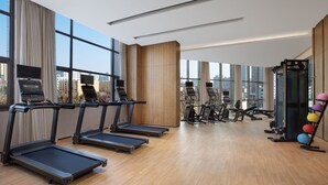 Un gimnasio moderno con cintas de correr, elípticas y pesas sueltas.