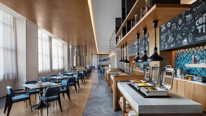 Un restaurante moderno con suelos de madera, sillas azules y una zona de bufé con recipientes de comida.