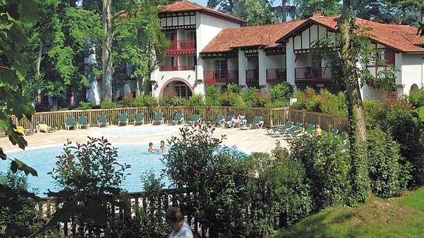 A hotel with a swimming pool surrounded by lush greenery and a wooden fence. - Apartment Basque Country Saint Jean Pied de Port (Uhart cize)