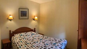 A bedroom with a bed, two wall-mounted lamps, a framed picture, and a window with curtains. - Apartment Basque Country Saint Jean Pied de Port (Uhart cize)