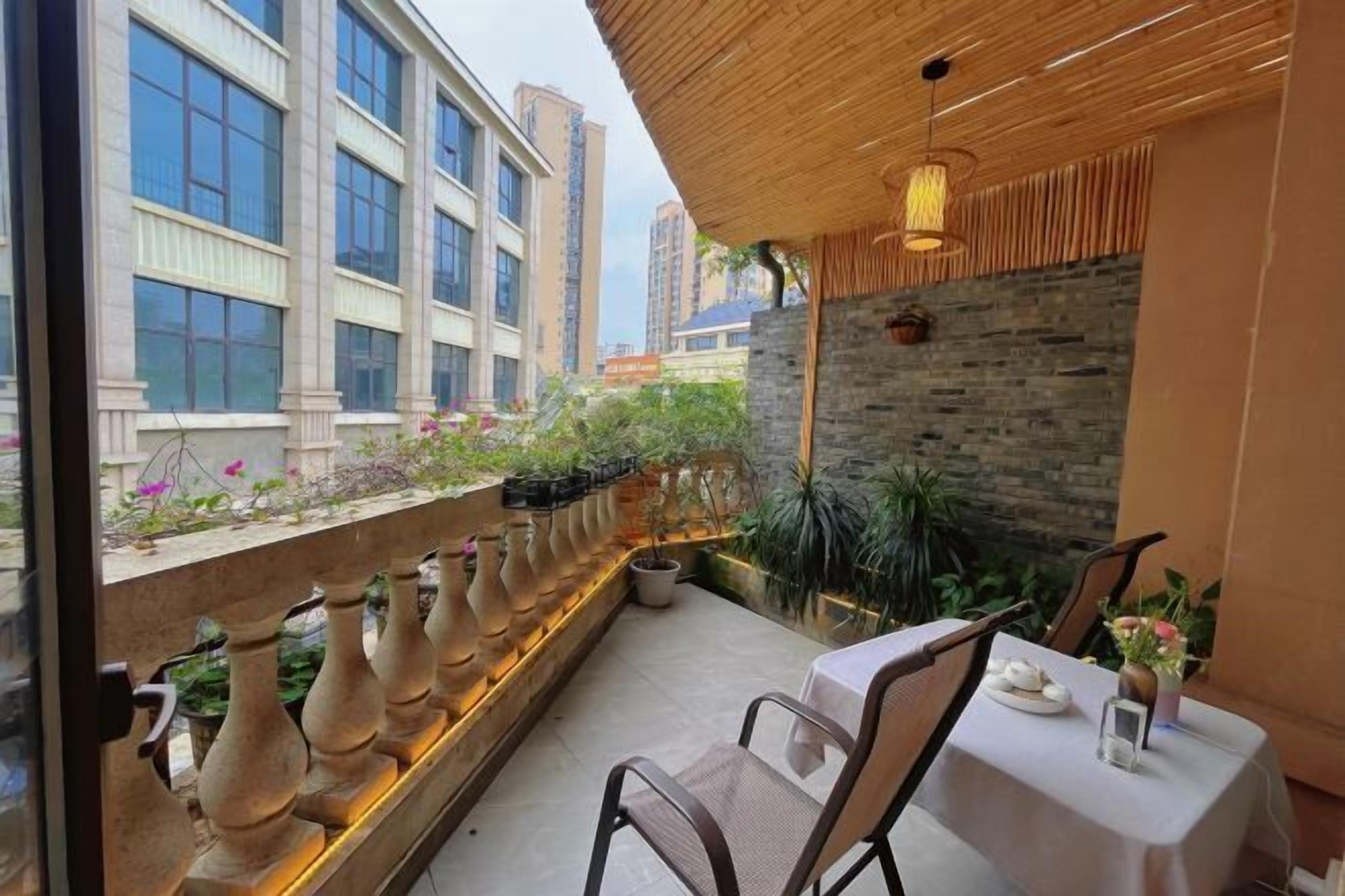 An outdoor dining area with a table and chairs, a stone wall, and a view of tall buildings.