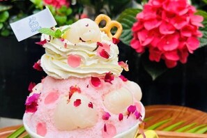 Un postre con capas rosadas y blancas, coronado con una hoja de menta y una pequeña bandera.