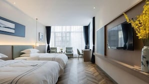 Habitación de hotel con dos camas, televisor, escritorio y ventana grande.