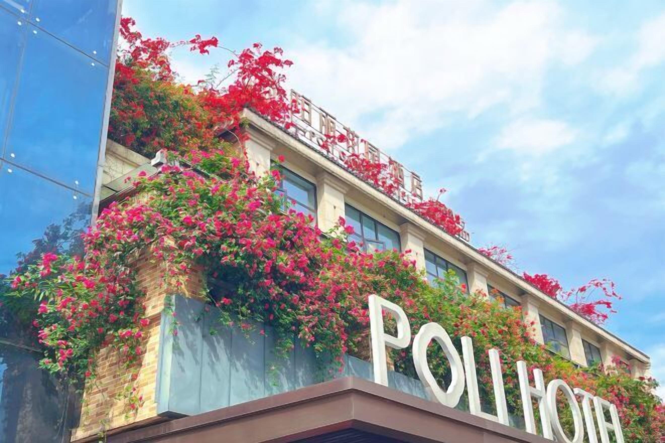 A hotel with a prominent 'POLHOTEL' sign, a brick facade, and red flowering vines.