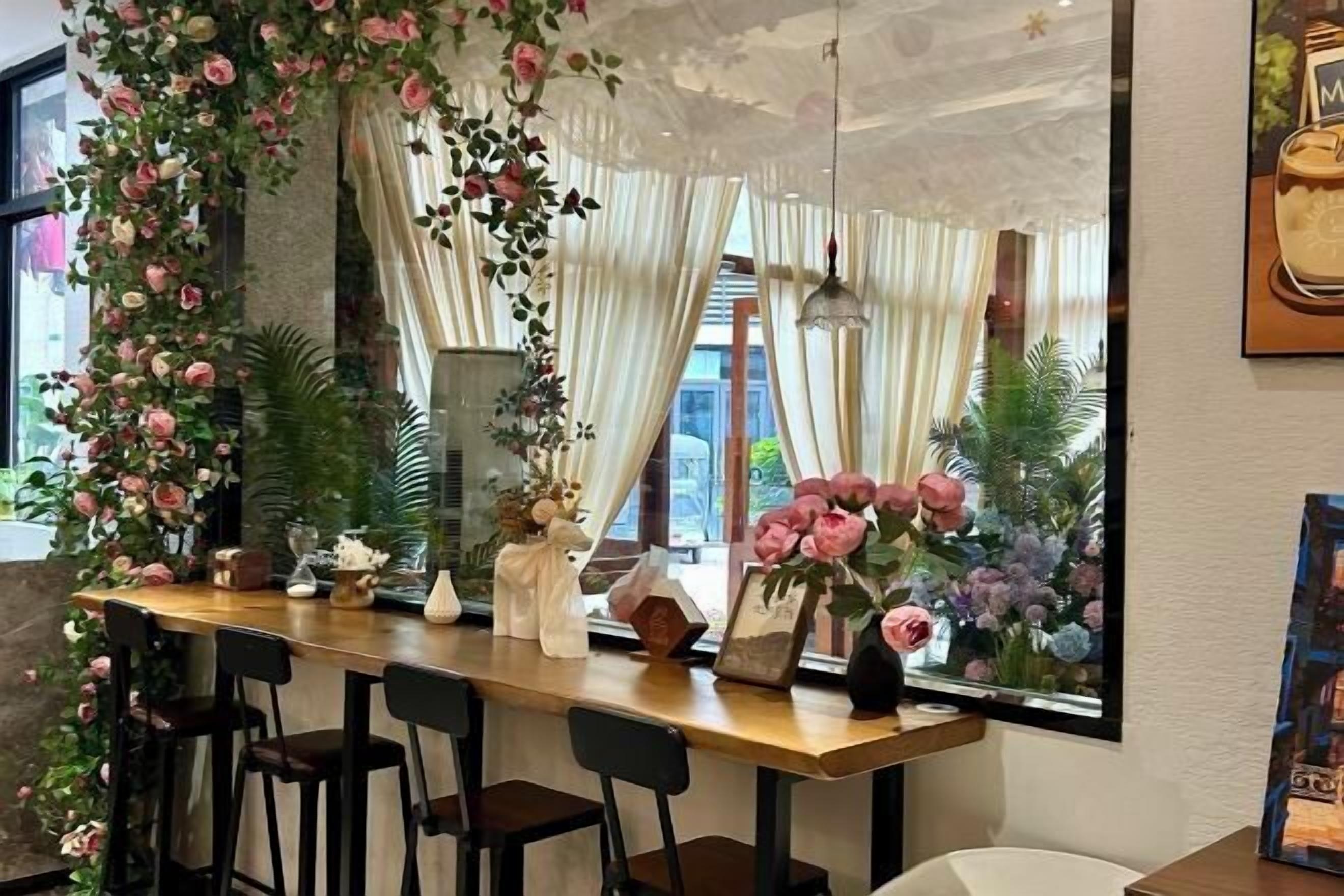 Uma área de bar com balcão de madeira, cadeiras pretas e plantas decorativas.