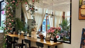 Uma área de bar com balcão de madeira, cadeiras pretas e plantas decorativas.