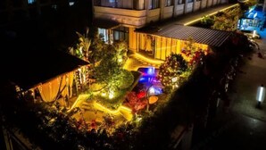 Um edifício com vários andares, entrada bem iluminada e área externa coberta com plantas.