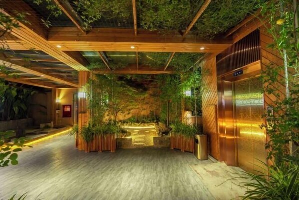 A modern lobby with wooden beams, green plants, and a reception desk. - Poli Garden Hotel (Qianwei County)