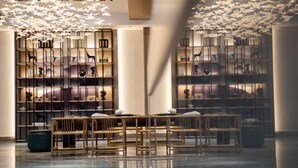 Un interior moderno con suelo reflectante, mobiliario de madera y un diseño de techo original con elementos colgantes.