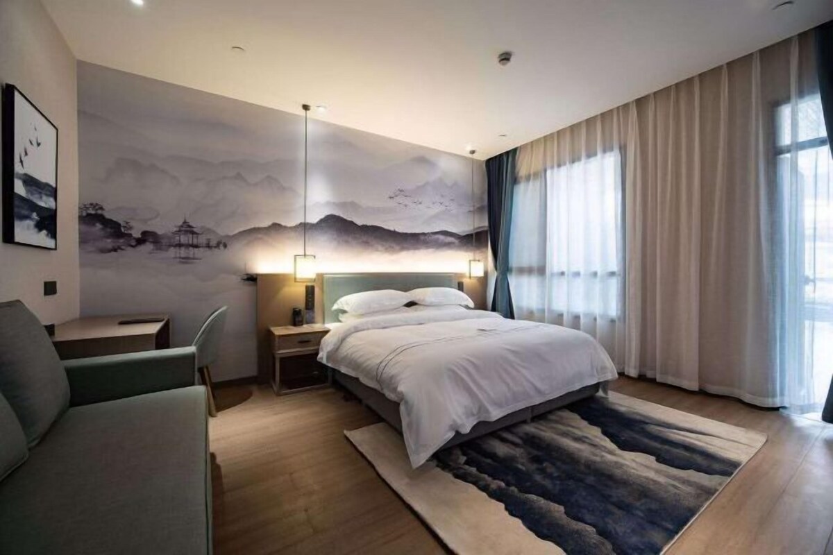 A modern hotel room with a bed, a desk, and a chair.