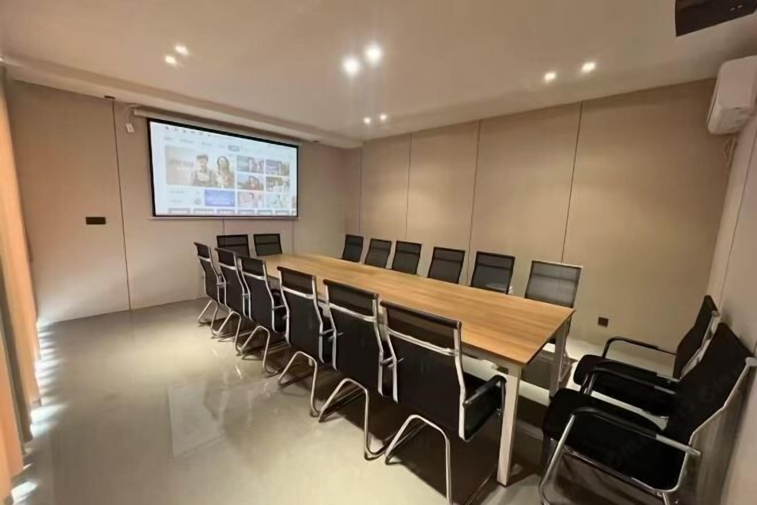 A conference room with a long table and chairs, a projector screen, and a tiled floor.