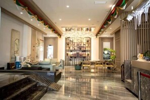 A spacious lobby with a reception desk, seating area, and a decorative fountain. - Poli Garden Hotel (Qianwei County)