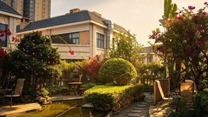 Un hotel con piscina, mobiliario exterior y abundante vegetación.