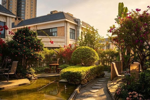 A hotel with a swimming pool, outdoor seating, and lush landscaping. - Poli Garden Hotel (Qianwei County)