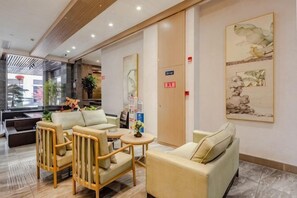 A hotel lobby with seating arrangements, a reception desk, and artwork on the walls. - Poli Garden Hotel (Qianwei County)