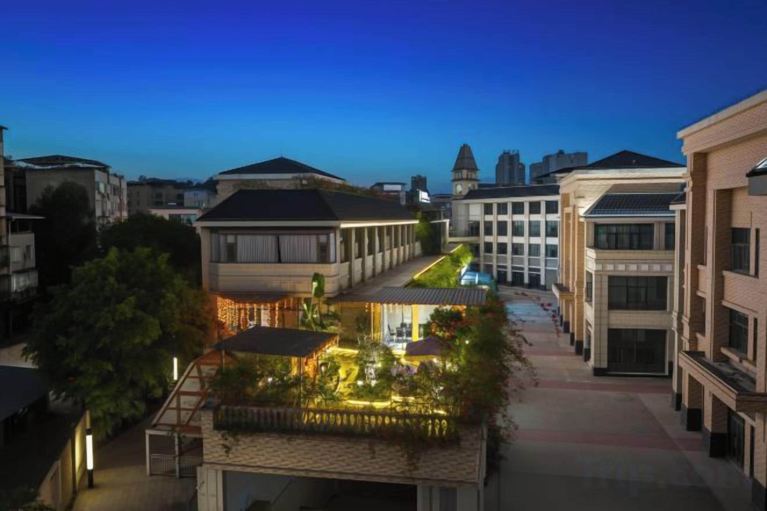 Un patio con jardín, un edificio con techo inclinado y otro edificio con techo plano.
