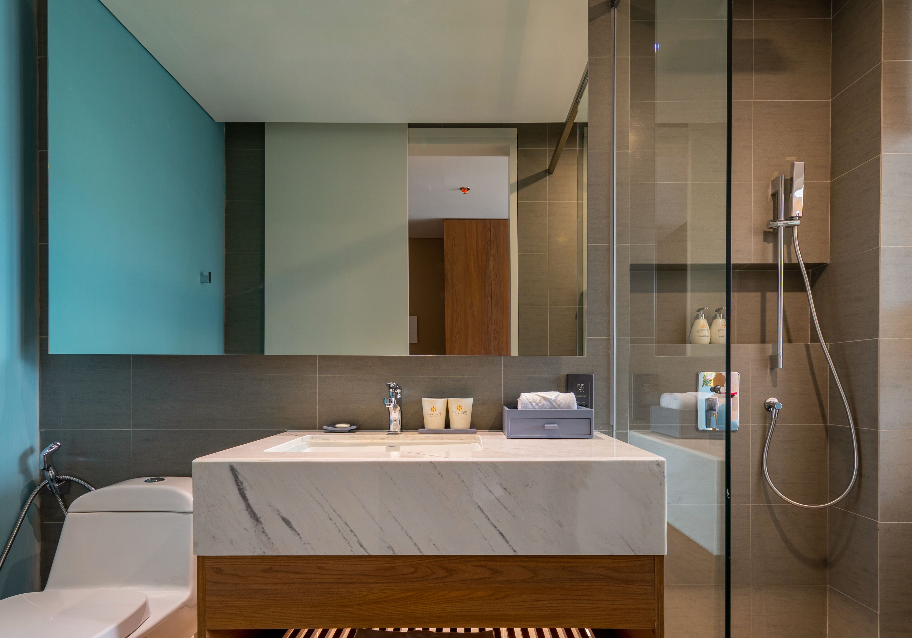 A modern bathroom with a marble sink, wooden vanity, and a glass-enclosed shower.