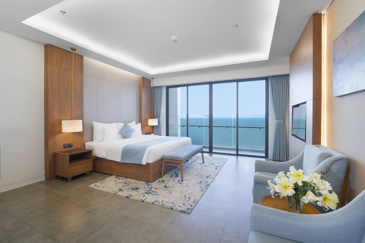 Un hotel moderno con una cama grande, una zona de estar y vistas al océano.