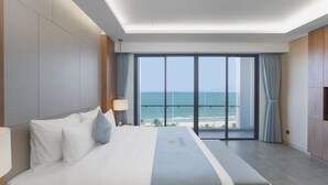 Een hotelkamer met een groot bed, uitzicht op zee en een balkon.