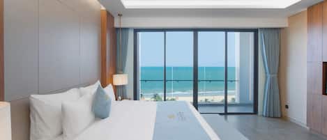 A hotel room with a large bed, a view of the ocean, and a balcony.