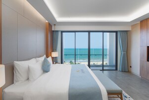 Quarto de hotel com cama grande, vista para o oceano e varanda.