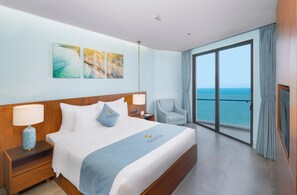 Ein Hotelzimmer mit Bett, Stuhl, Nachttisch, Lampe und Meerblick.
