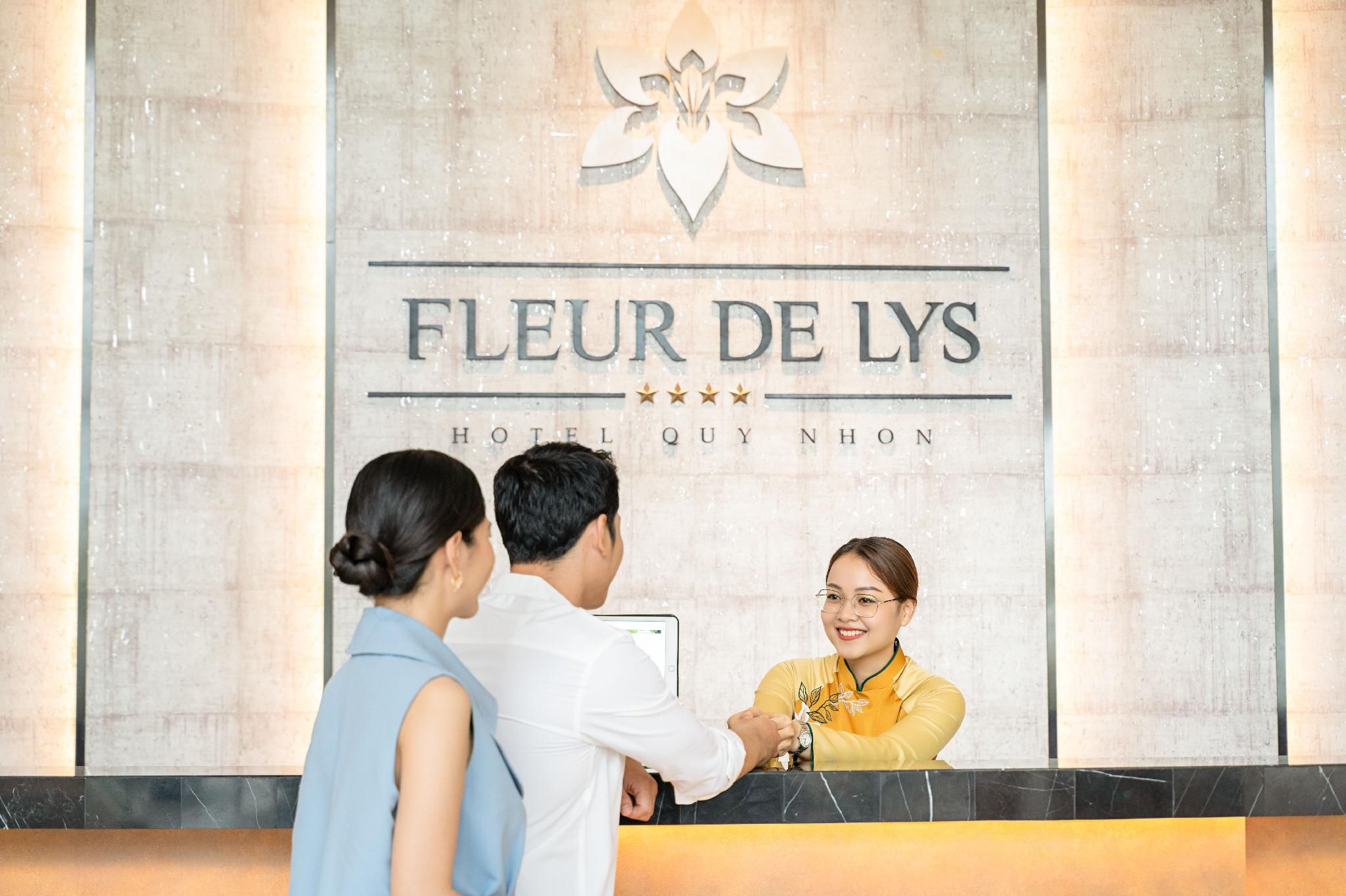 A hotel reception desk with a sign reading 'FLEUR DE LYS HOTEL QUY NHON'.