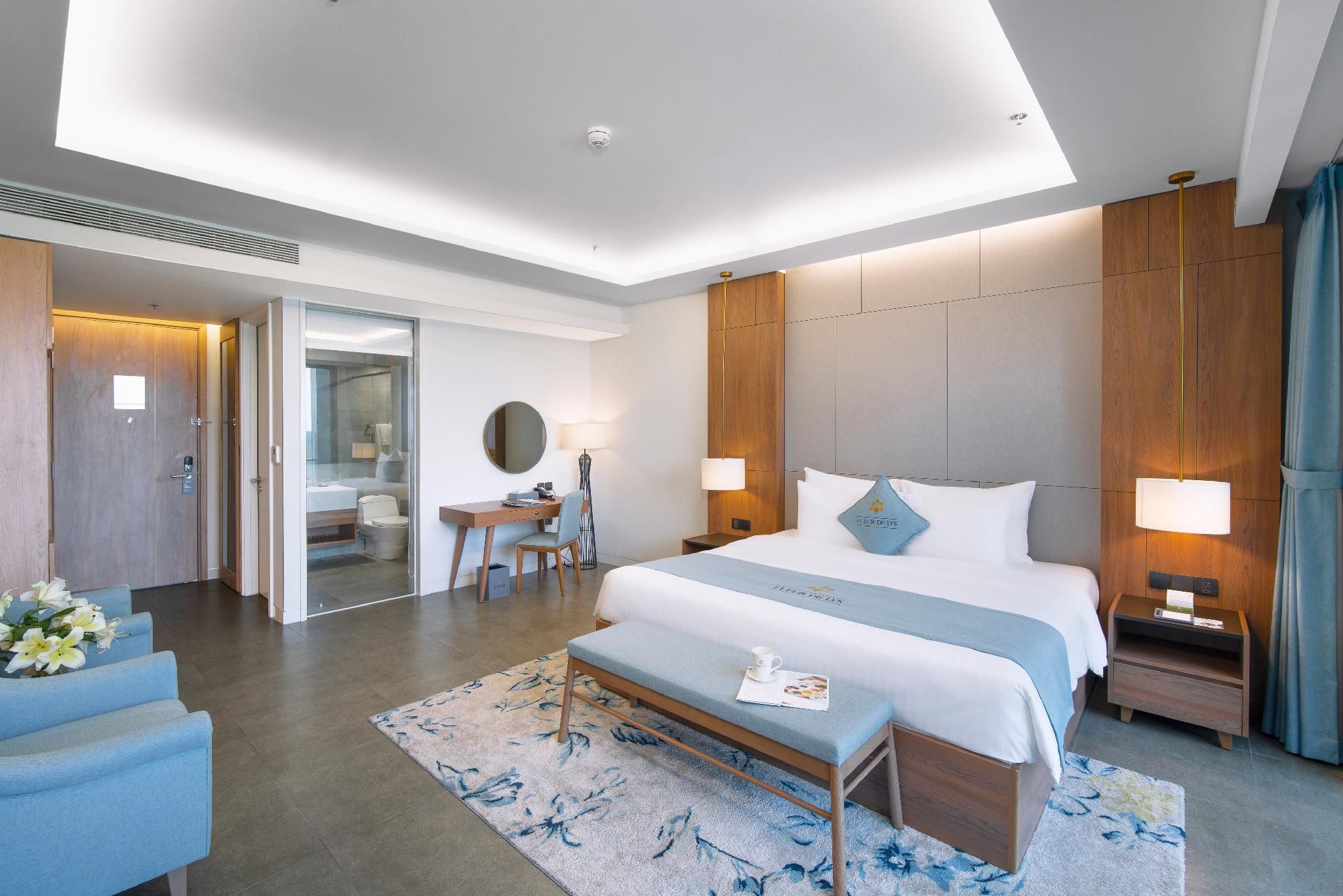 Een moderne hotelkamer met een groot bed, nachtkastjes, een bureau en een zithoek.