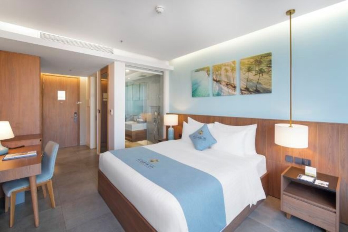 Een hotelkamer met een bed, nachtkastjes, een bureau met stoel, en een badkamer zichtbaar door een open deur.