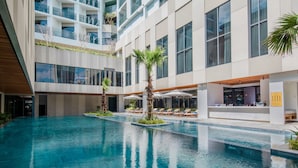 Un hôtel moderne doté d’une piscine centrale, de nombreux balcons et d’espaces de détente en plein air.