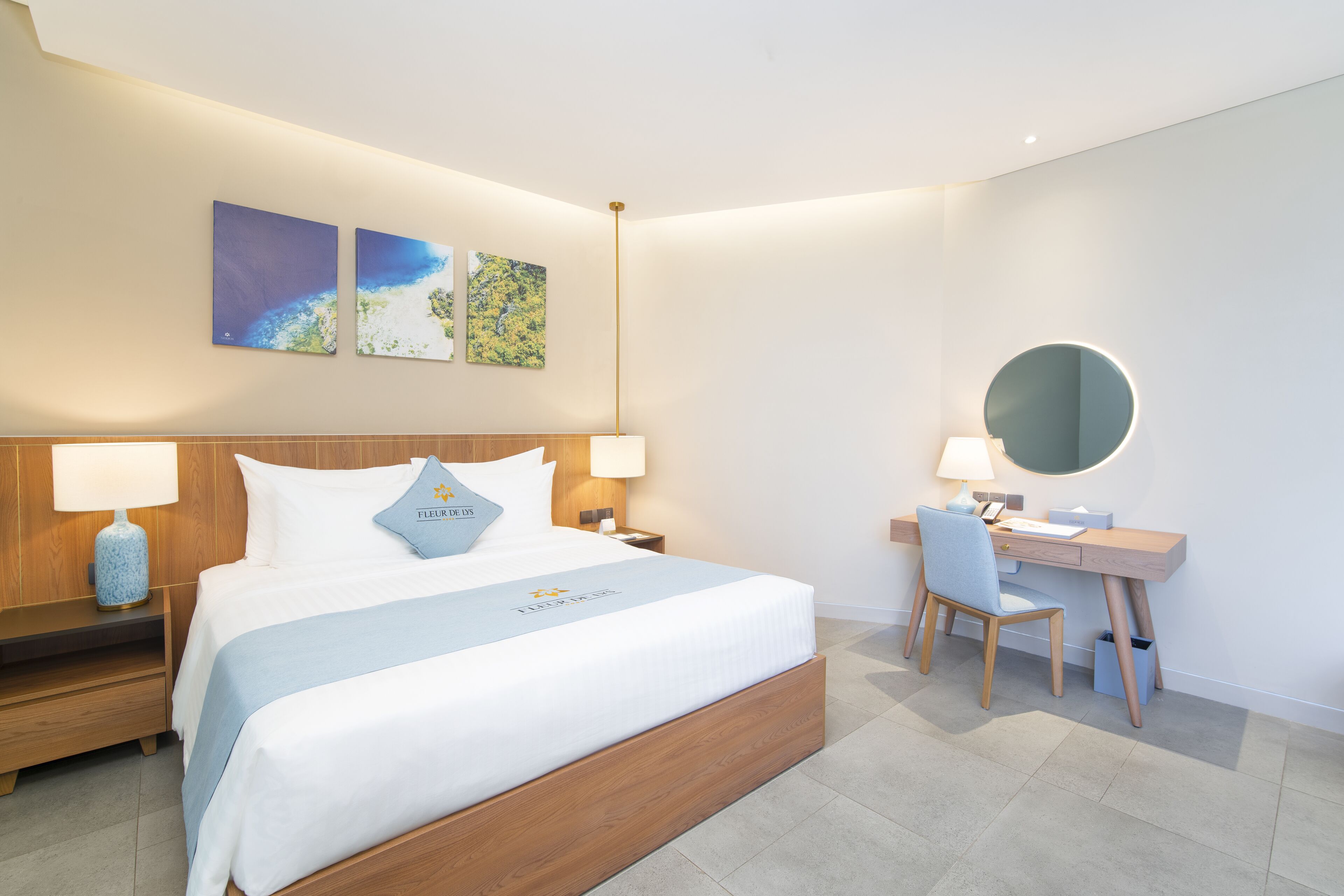 A modern hotel room with a wooden bed, a desk, and a round mirror.