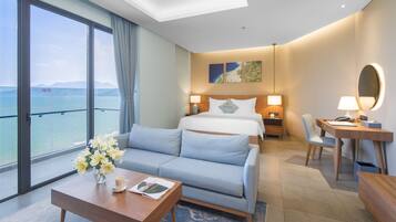 Quarto de hotel moderno com uma varanda ampla, uma cama, uma escrivaninha e um sofá.