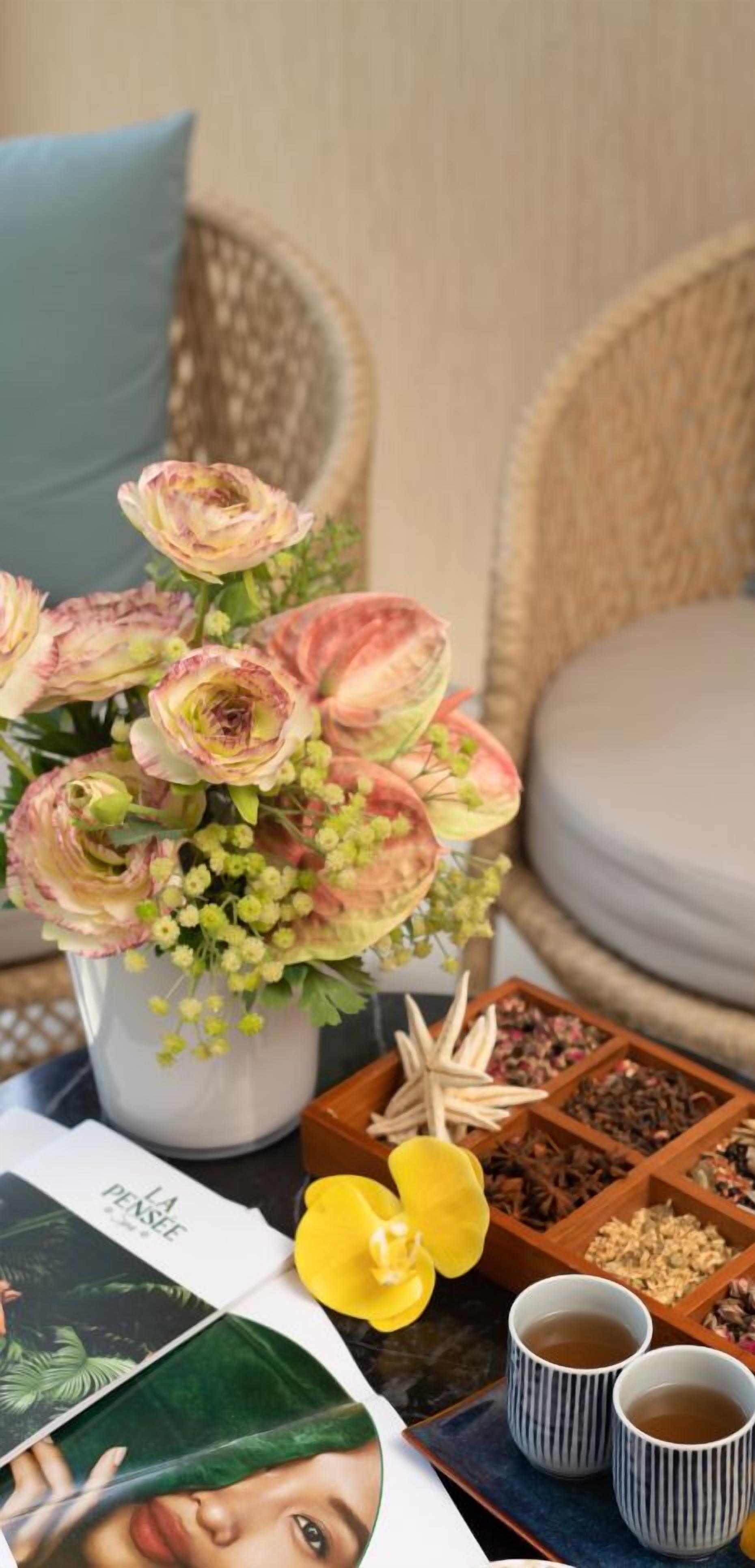 A table with a floral arrangement, a book, and two cups of tea.